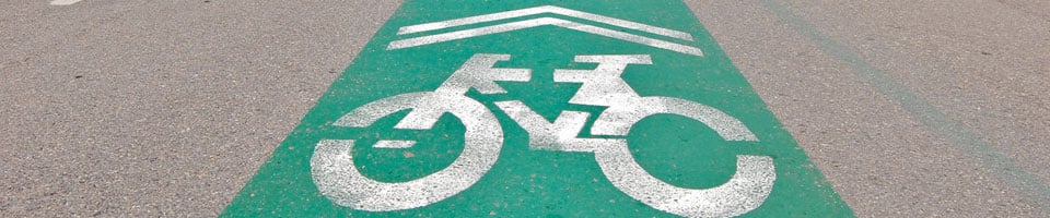 Bicycle lane marked on a roadway with green paint and a white bike symbol. 