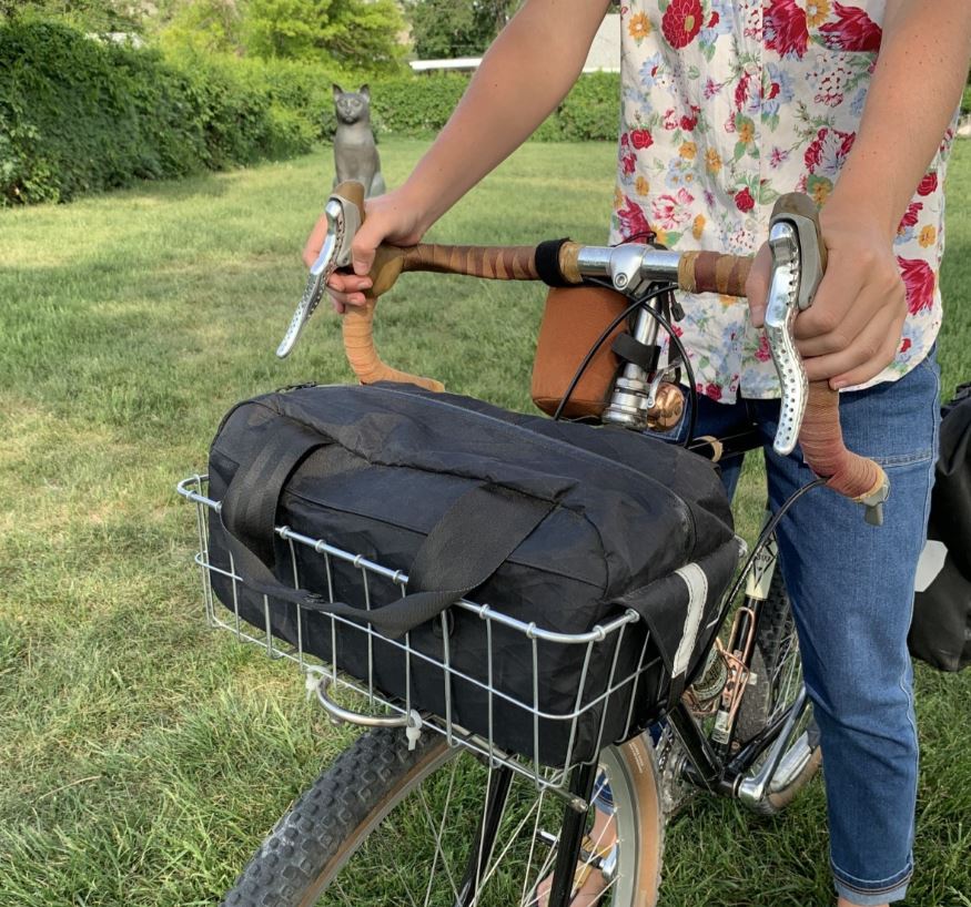 Bicycle with front basket carrying a bag.
