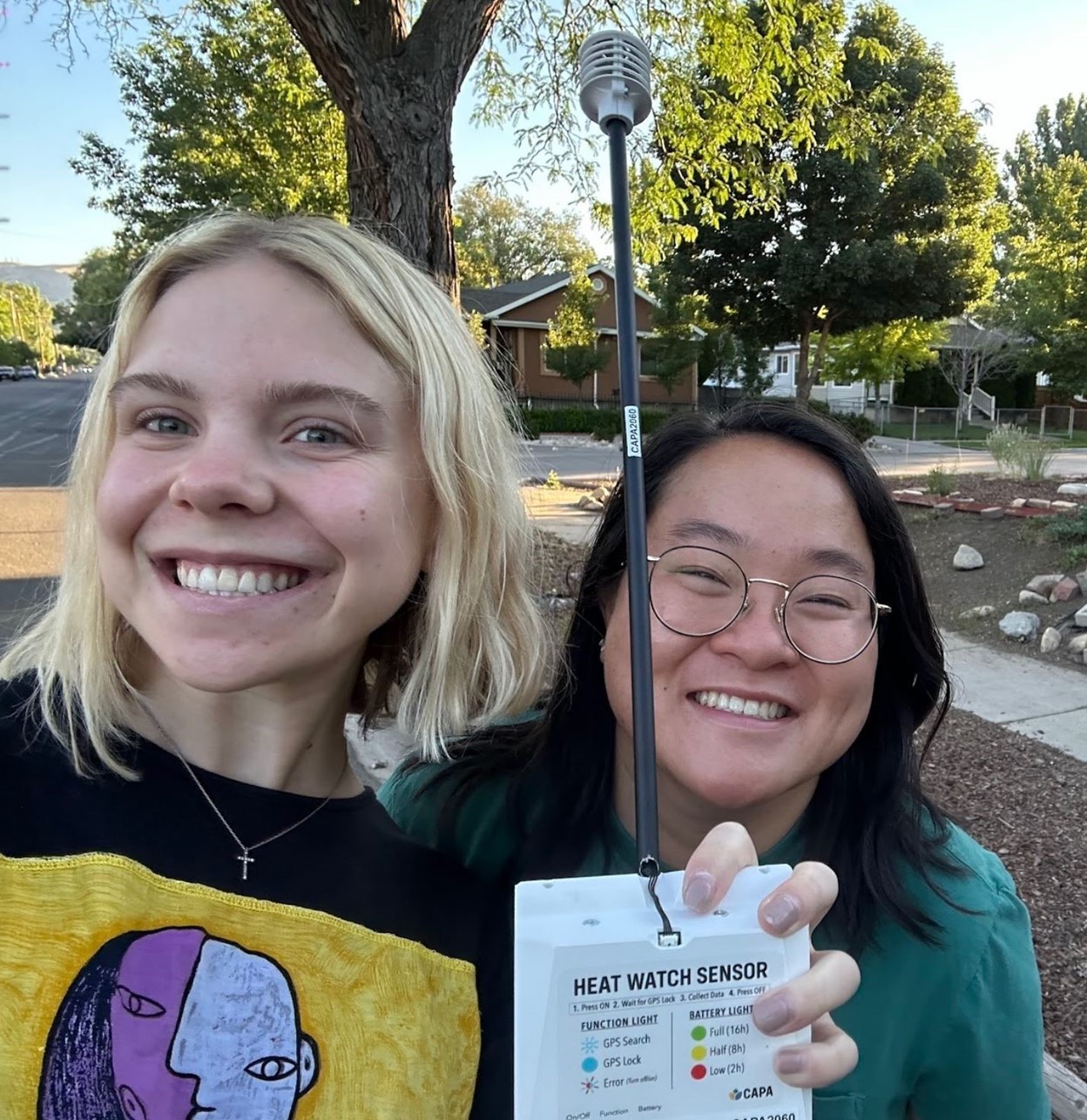 Picture of two people outside holding a heat watch sensor and guide.